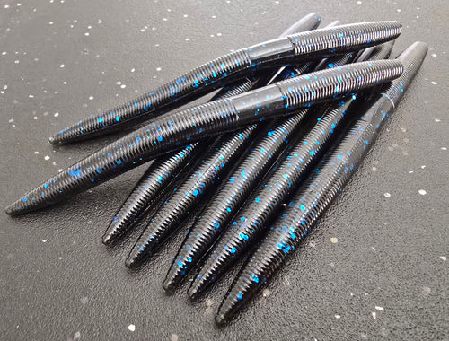Black and blue sapper sticks soft plastic worms on a gray surface