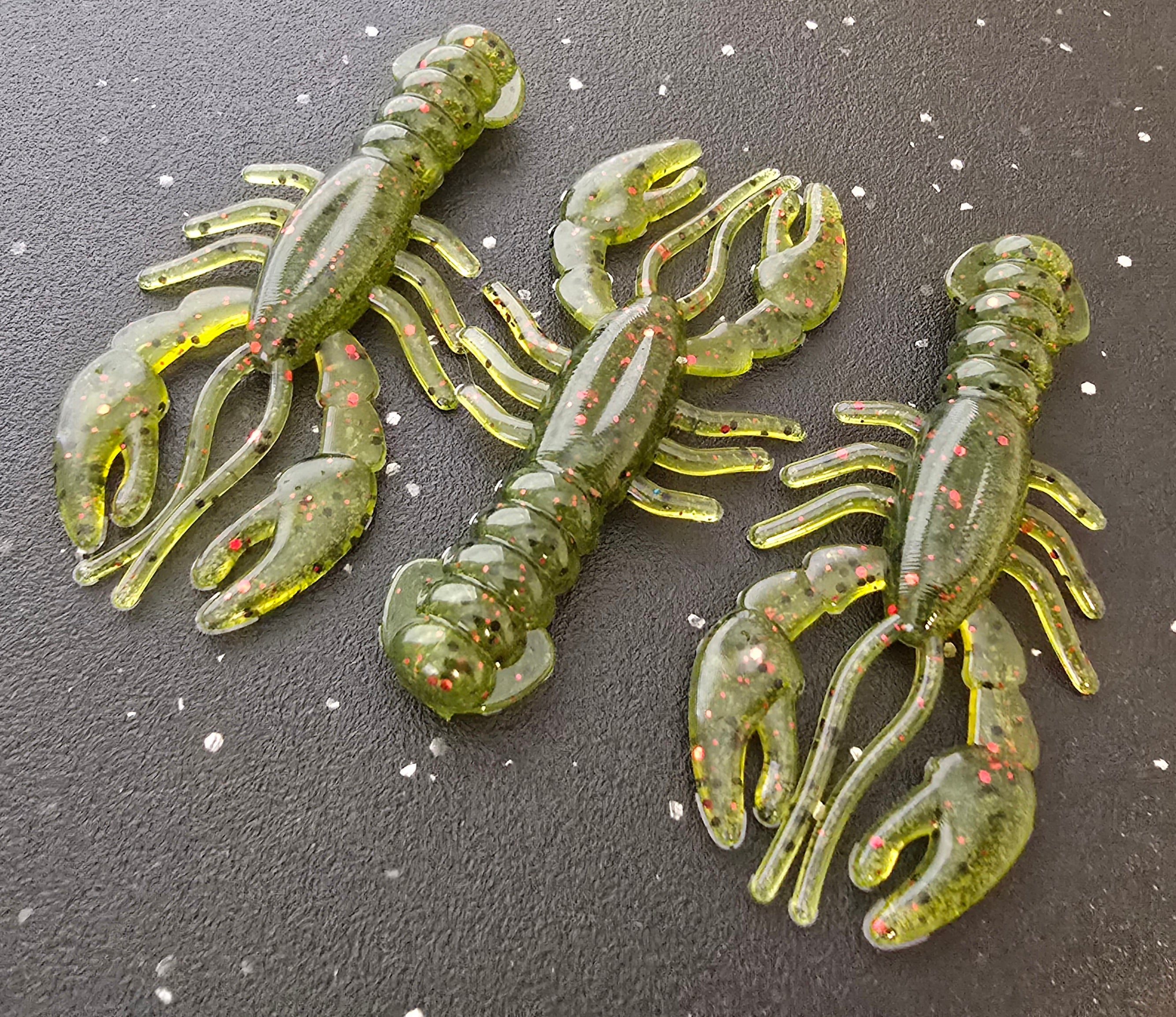 Three sapper baits watermelon recon crawfish-shaped fishing lures on a dark surface